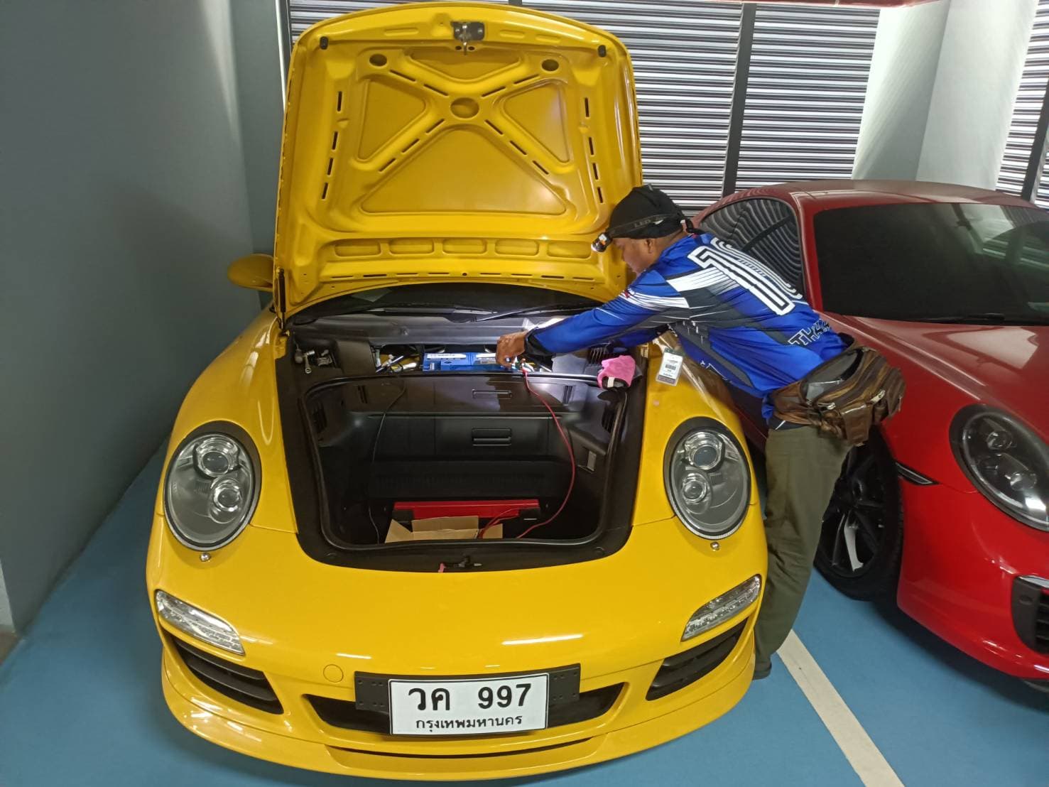 ช่างกำลังเปลี่ยนแบตเตอรี่รถยนต์ที่จุดจอดรถ